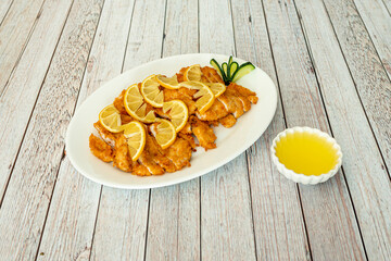 Tray of sliced breaded chicken breast fillets and Chinese recipe lemon juice and sauce