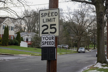A 25 mile per hour speed limit sign on a wooden utility pole on the side of a community street