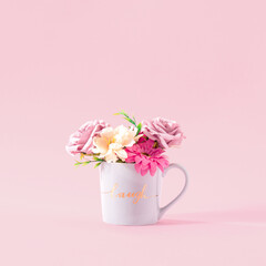 Concept of a grey cup full of fresh flowers on pastel pink background. .Creative warm natural drink. Are you in the mood for a cup of morning coffee?