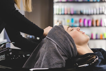 Master woman hairdresser carefully wraps the girl's head in a towel before styling in a beauty...