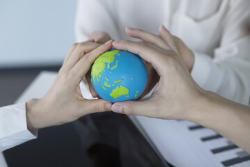 Global business, technology and people concept.Business people holding globe in meeting
