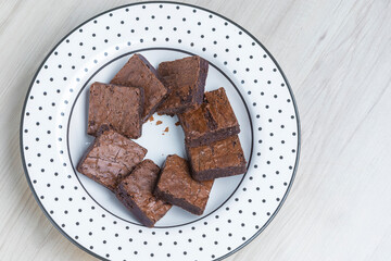 brownie pieces arranged on a plate of black polka dots on a wooden base viewed from above
