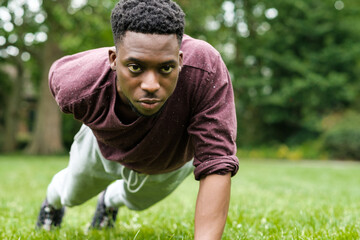 Young black man doing push ups with one hand.