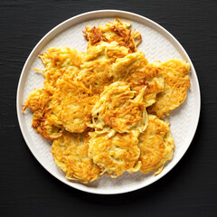 Homemade Potato Pancakes Latkes with Apple Sauce and Sour Cream on a black background, top view. Flat lay, overhead, from above.