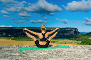 Young woman doing yoga fitness exercise in the mountains. The concept of yoga, fitness, meditation, healthy lifestyle, weight loss.