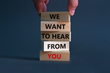 Support and help symbol. Wooden blocks with words 'we want to hear from you'. Businessman hand. Beautiful grey background, copy space. Business, help and support concept.