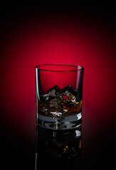 Glass of Kentucky Bourbon with ice on reflective surface on black background with circular red spot