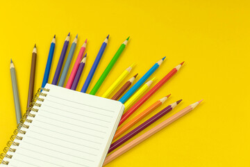 Obraz premium Creative back to school desktop background with blank notebook and color drawing pencils