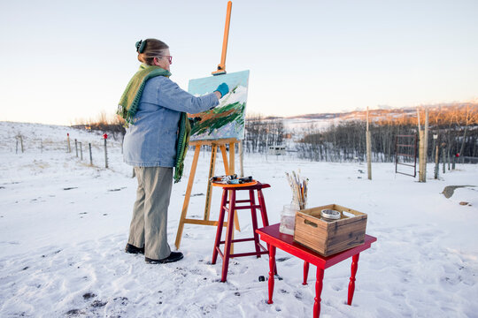 Woman painting in winter landscape