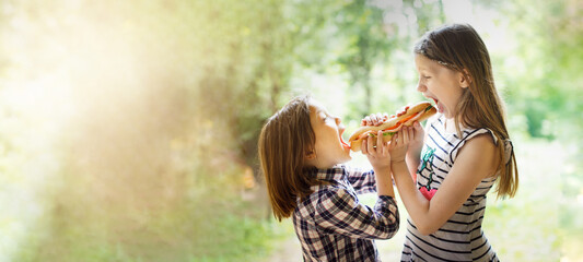 Take a bite. Funny cute Caucasian children are eating together a big sandwich. Concept food on the...