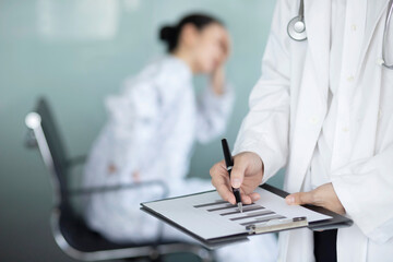 Close up of doctor writing on clipboard