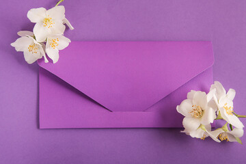 Violet postal envelope with space for text, Beautiful spring white flowers in on violet paper background. Top view, flat lay