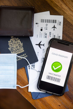 Face mask, passport, airplane ticket and covid passport on smart phone