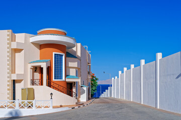 Luxurious modern guest houses with terracotta walls, high windows and a closed area are located along the street leading to the sea. Vacation concept, architectural facade background.
