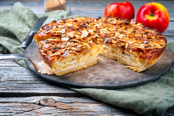 Traditional apple pie torta di mele cremosa with almond flakes served as close-up on a rustic...
