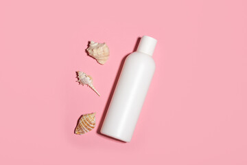 White cosmetic bottle with face cream or lotion and telana against a pink background with seashells. Sun cream, summer cosmetics.