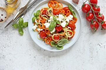 Warm salad from vegetable spaghetti , backed cherry tomatoes and goat cheese. Flat layot, copy space