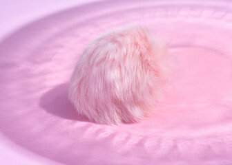 Pink fluffy ball on pink paper in a beautiful shadow. Creative concept