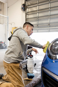 Male Worker Polishing Car In Auto Body Detailing Shop