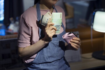 Woman holding coin purse with money at home