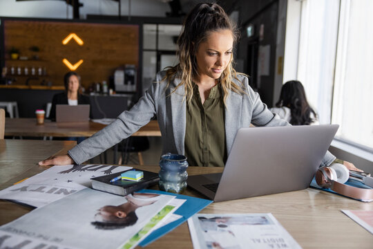 Creative Businesswoman With Proofs Using Laptop In Coworking Space