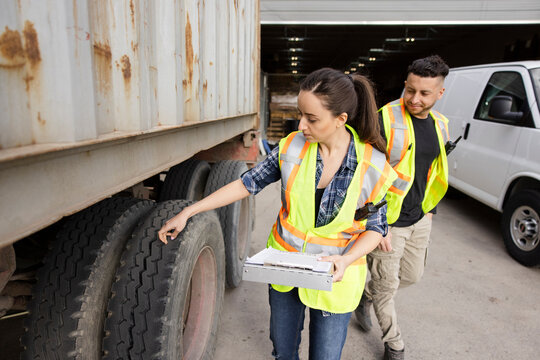 Warehouse workers with clipboard inspecting delivery truck tires