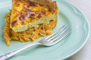 detail of a slice of quiche lorraine flavored chicken with cream cheese, wooden base
