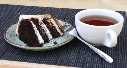 A piece of cake on a ceramic plate and a cup of tea