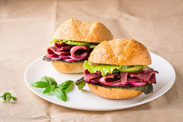 Ready-to-eat hamburgers with pastrami, vegetables and basil on a plate on craft paper. American fast food