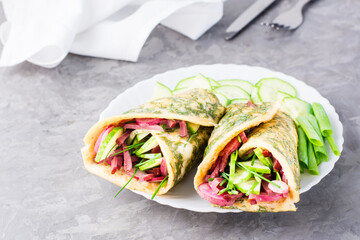 Egg rolls filled with pastrami, vegetables and green onions on a plate on the table. Hearty and high-calorie snack