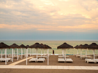 Hombre paseando entre los parasoles de la playa al atardecer