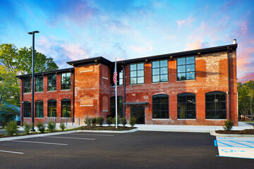 View of brick mill façade with parking lot and American flag © Brian