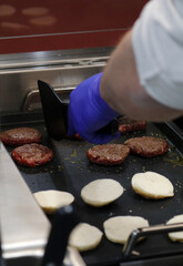 cocinero fríe hamburguesas a la plancha con sus panecillos