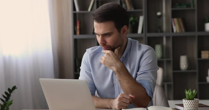 Pensive 35s male employee sit at workplace desk working on wireless computer, makes thinks over creative task, doing telecommute, busy in brainwork, workflow, learn new software, challenge concept