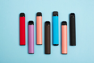 Set of colorful disposable electronic cigarettes on a blue background. The concept of modern...