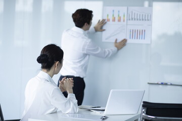 Businessman Explaining and Pointing at Chart on Board