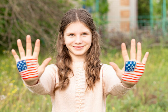Cute little child girl with painted hands in American flag color. USA celebrate 4th of July. Independence Day, memorial day, flag day June 14