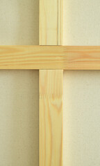 Wooden bars in the shape of a cross lie on a fabric background. 