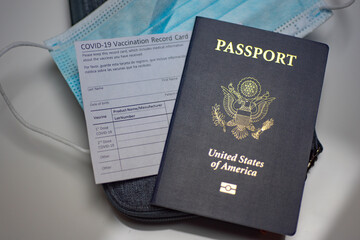 Covid-19 Vaccination Recosr card next to the passport of USA and Medical blue mask. Travel after...