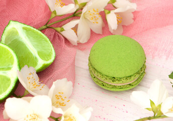 Obraz na płótnie Canvas green macaroon cake on a pink background with a slice of lime. Lime macaroon with green cream. Round mint dessert. High quality photo