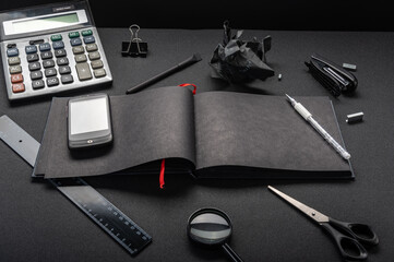 Black magazine on a black table. Accounts department and office. Smartphone and calculator on the...