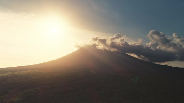 Aerial sunset over volcano erupt. Silhouette of mount. Countryside nobody nature landscape. Sun rays light above tropical green trees, plants and hills. Landmark of Mayon mountain, Philippines, Asia
