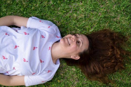 Retrato de una mujer joven guapa caucasica riendose tumbada en la hierba