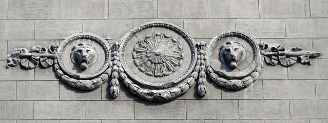 The facade of an old building decorated with a plaster lion
