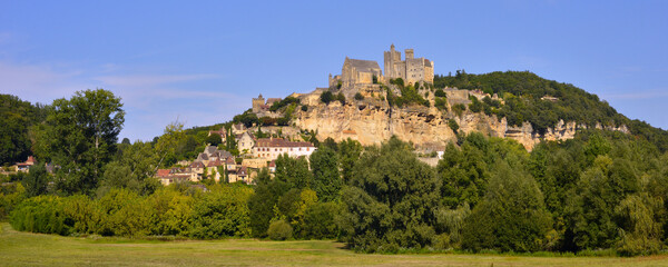 Panoramique haut perché sous un ciel bleu, le village de Beynac-et-Cazenac (24220) sur son rocher,...
