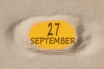 September 27. 27th day of the month, calendar date. Hole in sand. Yellow background is visible through hole. Autumn month, day of the year concept