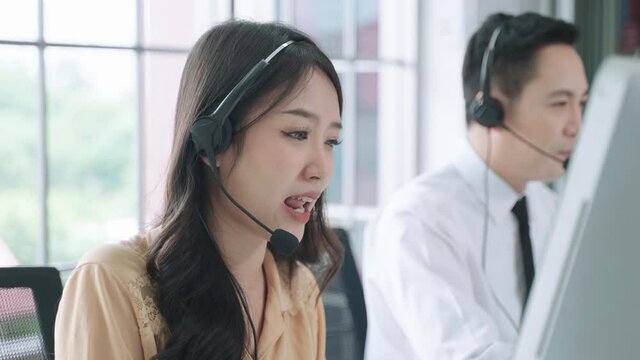 50p frame rate footage of asian woman call center, Customer support agent or call center with headset works on desktop computer while supporting the customer on phone call. Operator service business r