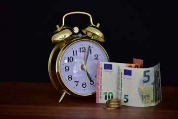 money and alarm clock on black background