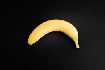 One single yellow banana isolated on black background