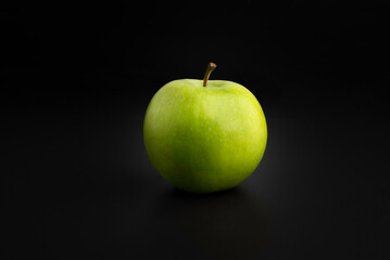 Green apple on a black background close up